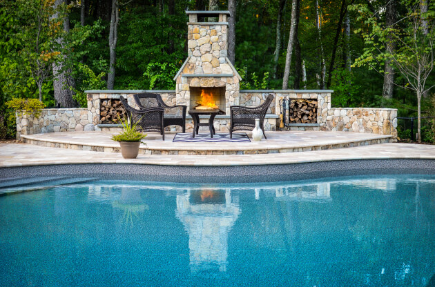 Pool with a fire pit and chairs at the end.