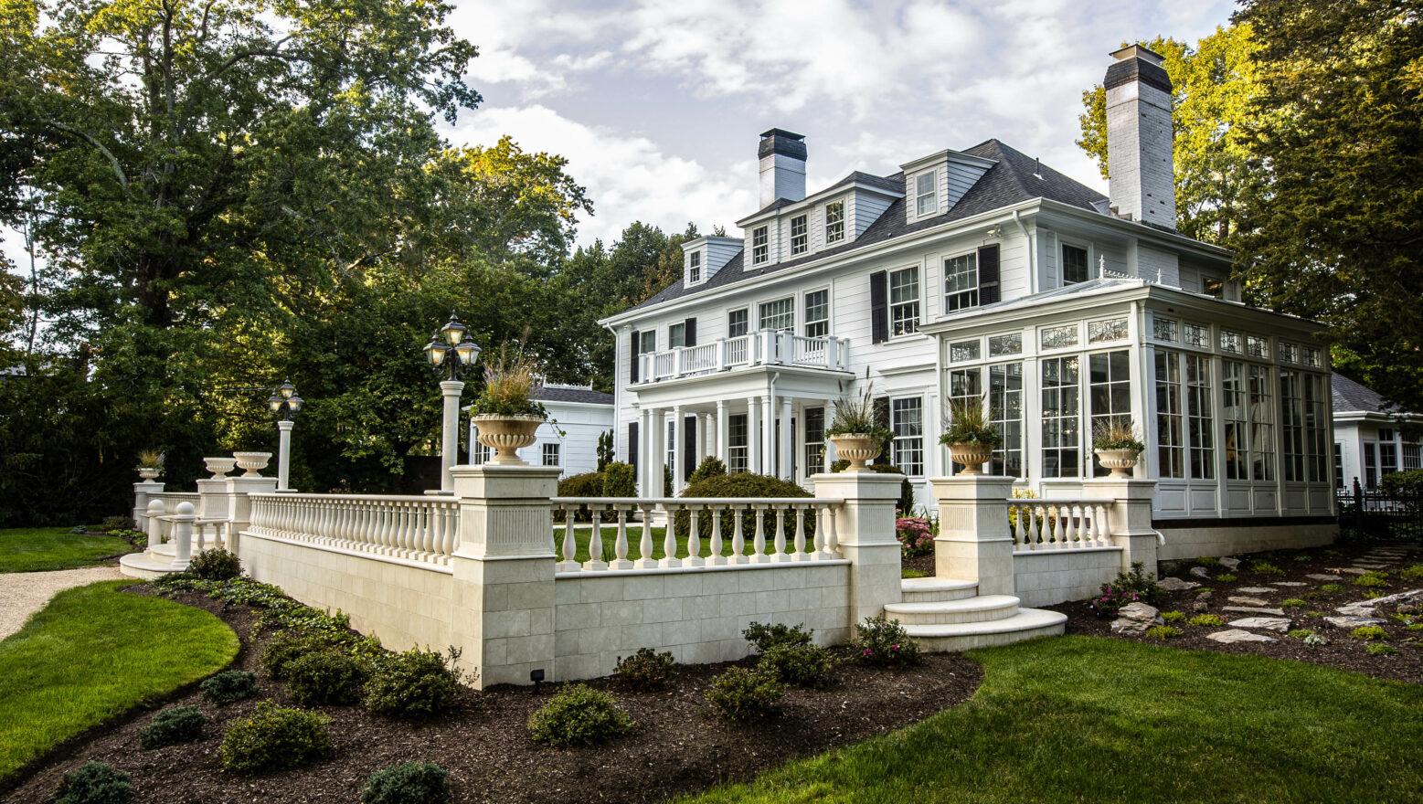 A residential courtyard built by Dex by Terra in Natick, MA. Stone fencing and steps with elegant landscaping.