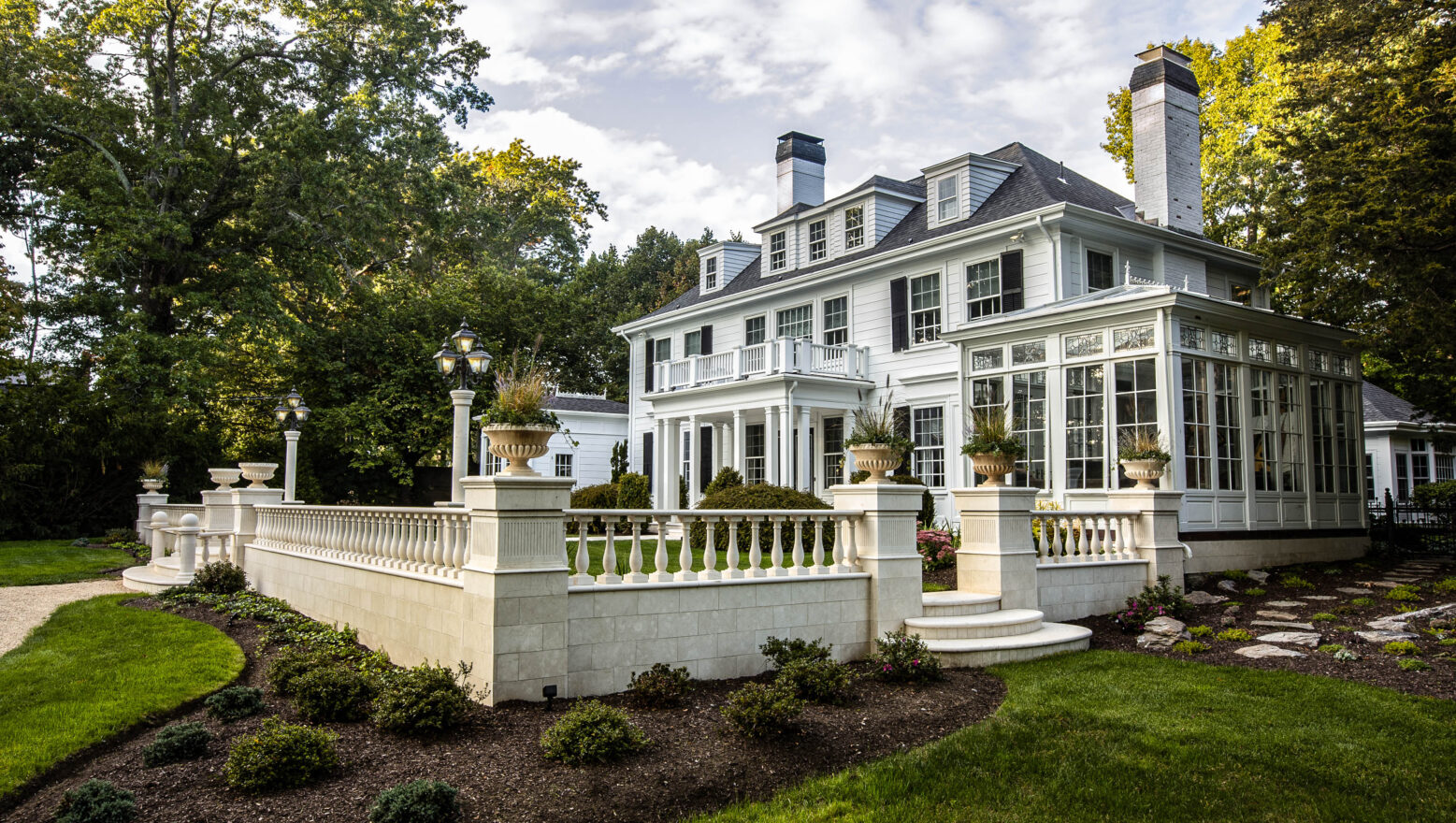 A residential courtyard built by Dex by Terra in Natick, MA. Stone fencing and steps with elegant landscaping.