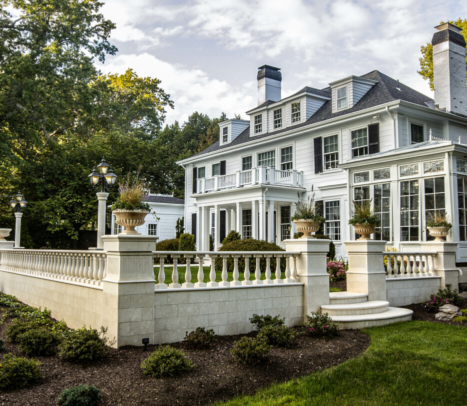 A residential courtyard built by Dex by Terra in Natick, MA. Stone fencing and steps with elegant landscaping.