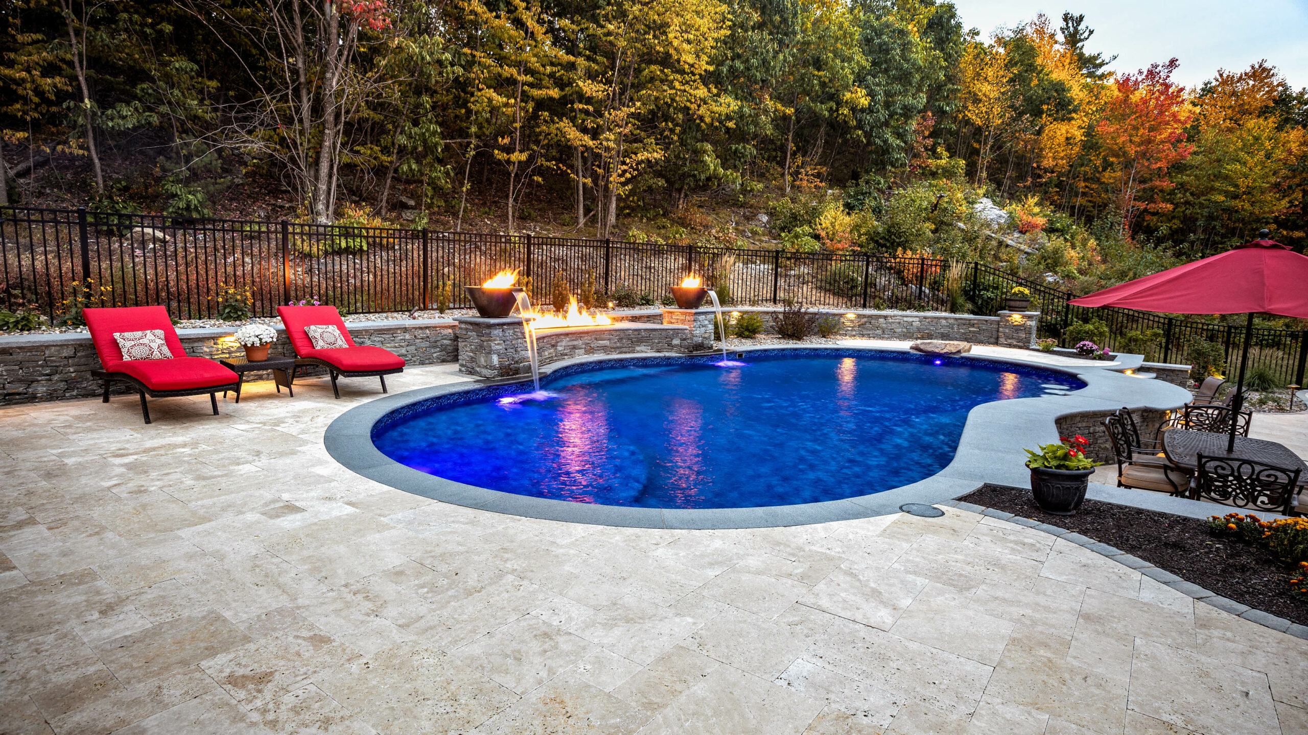 Pool area with lounge chairs an fire pits and fountains.