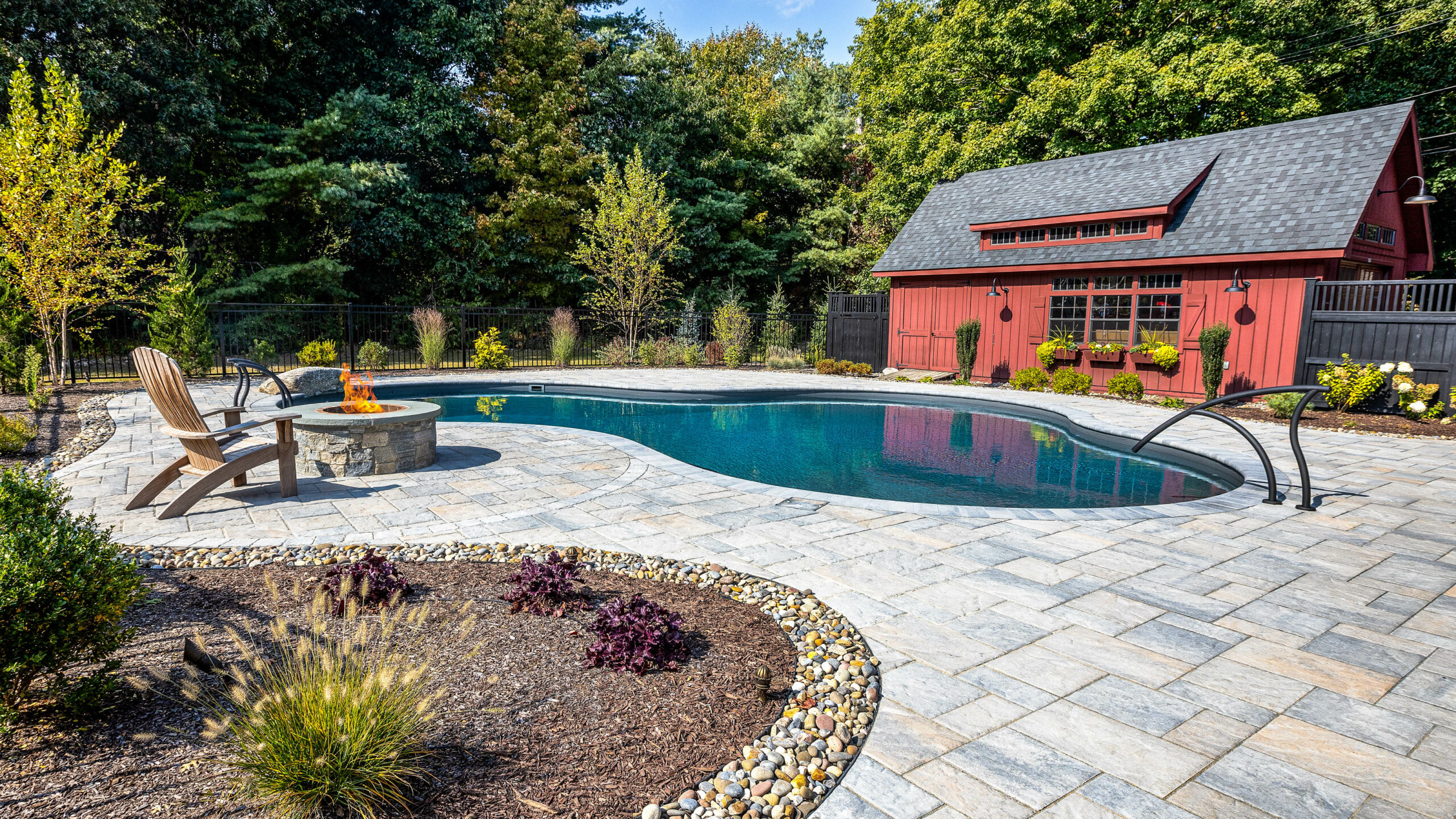 Pool with lounge chairs and a fire pit.
