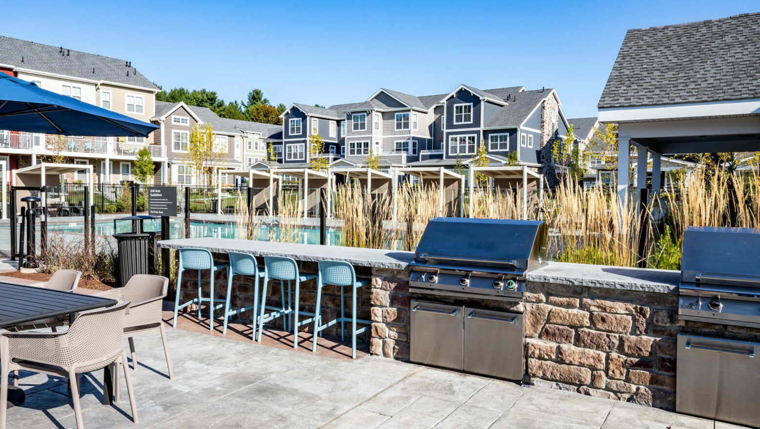 Outside BBQ and stools by a pool at Avalon Apartments. Dex by Terra design-build project.