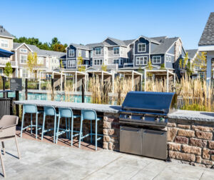 Outside BBQ and stools by a pool.