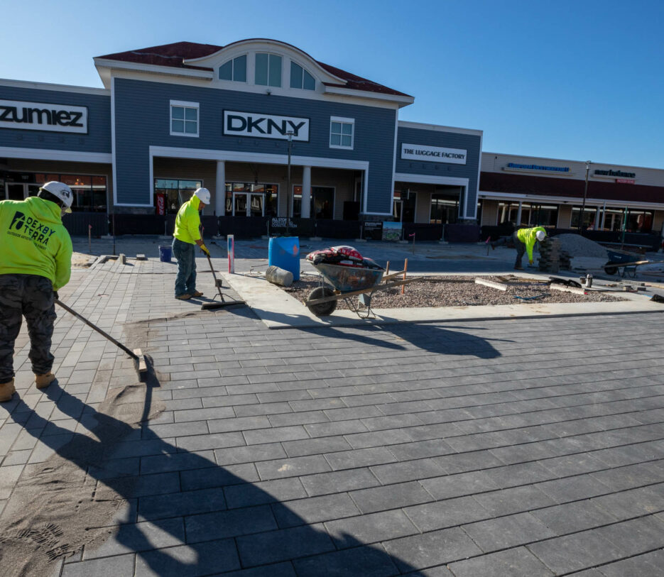 Workers setting pavers at a shopping center.