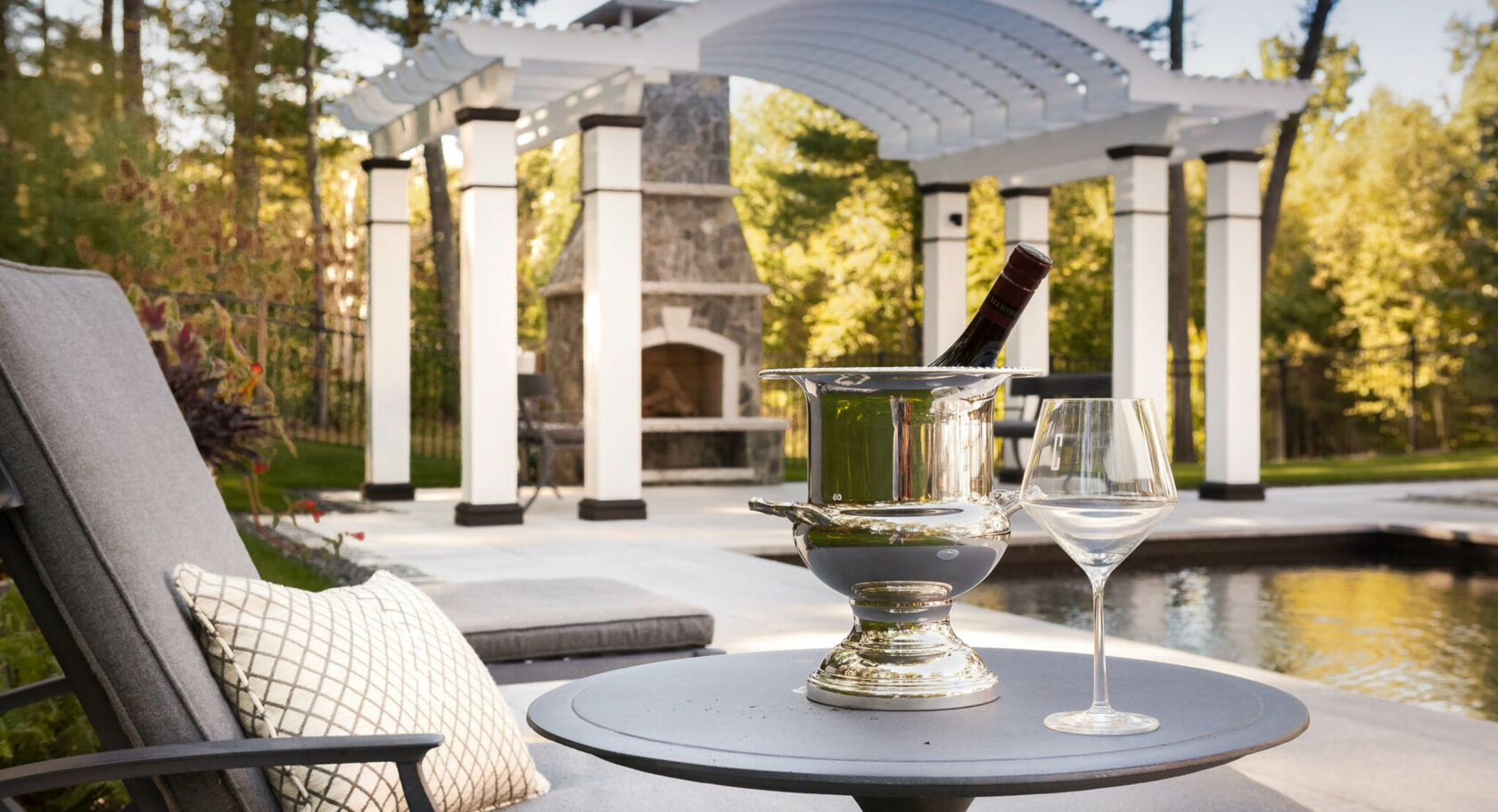 Wine on table next to inground pool with pergola. Dex by Terra design-build project in Massachusetts.