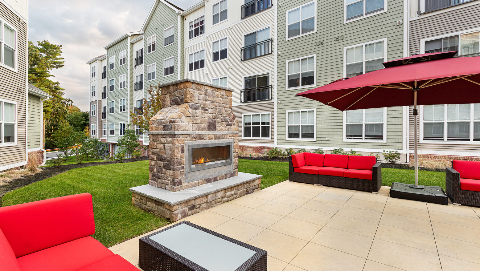 Patio and outdoor fireplace with couches at Eli Apartments in Sharon, MA. Dex by Terra landscape design-build project.