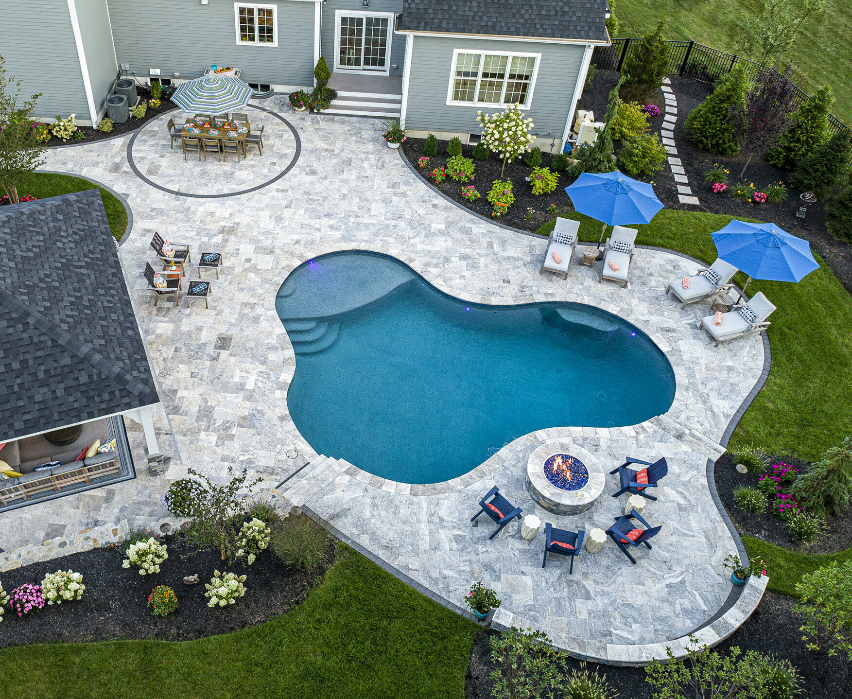 Drone view of pool, travertine pool deck, and fire pit. A Dex by Terra residential design-build project in Norfolk, MA.