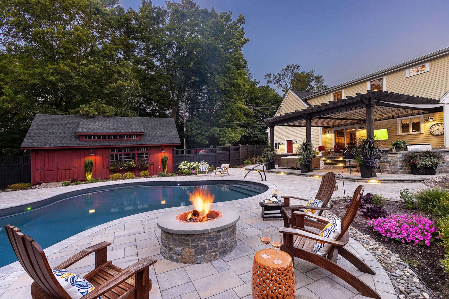 Fire pit on paver pool deck with outdoor kitchen and patio. Dex by Terra Residential Landscape Design-Build in Stow, MA.