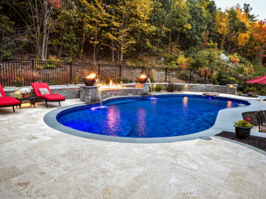 Pool area with lounge chairs an fire pits and fountains.