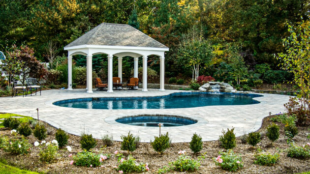 Pool with a water fountain and a cabana.