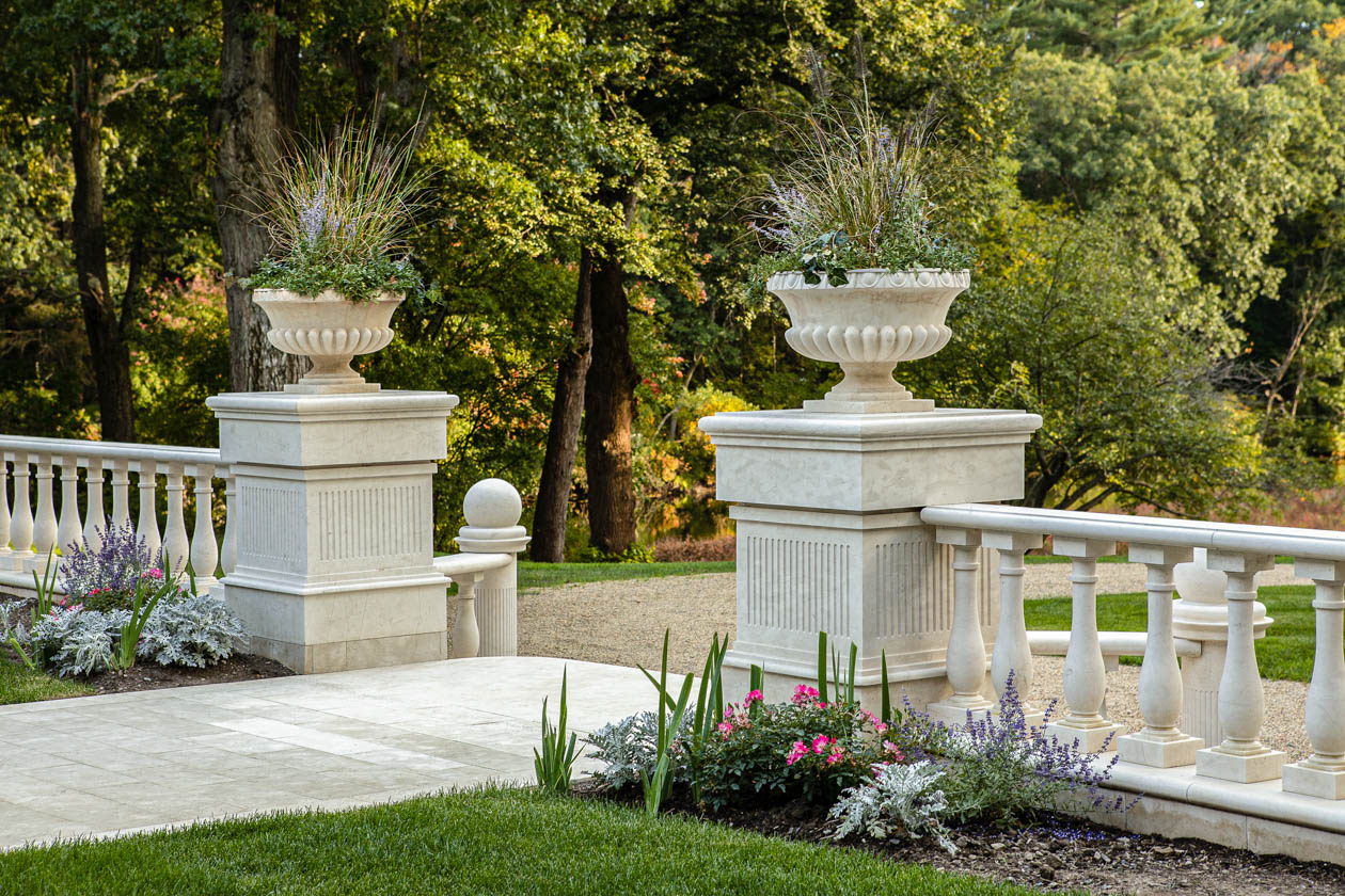 Marble columns with planters on top flanking courtyard walkway. Dex by Terra landscape design-build in Natick, Massachusetts.