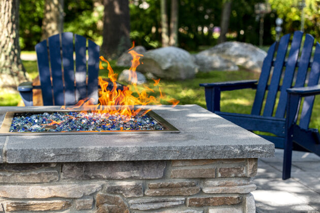 Stone veneer gas fire pit with chairs. Dex by Terra commercial hardscape project in Concord, NH.