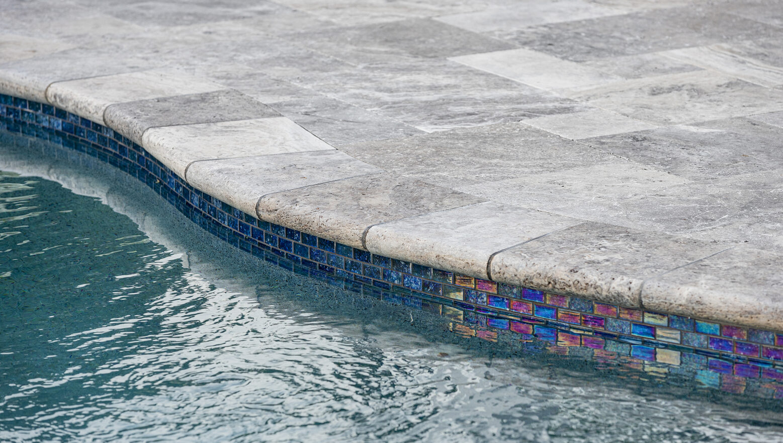 Detail of pool tile and travertine pool deck. Dex by Terra pool design-build project in Norfolk, MA.