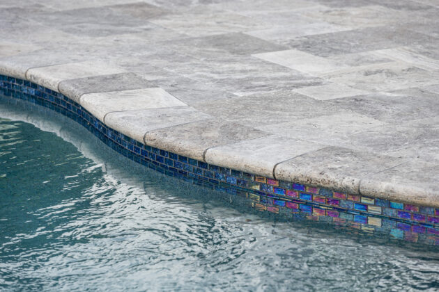 Detail of pool tile and travertine pool deck. Dex by Terra pool design-build project in Norfolk, MA.