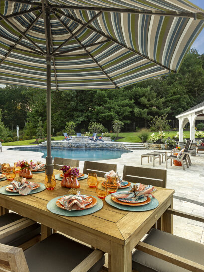 Dining table overlooks pool, pergola and outdoor kitchen. Landscape design-build by Dex by Terra in Norfolk, MA.