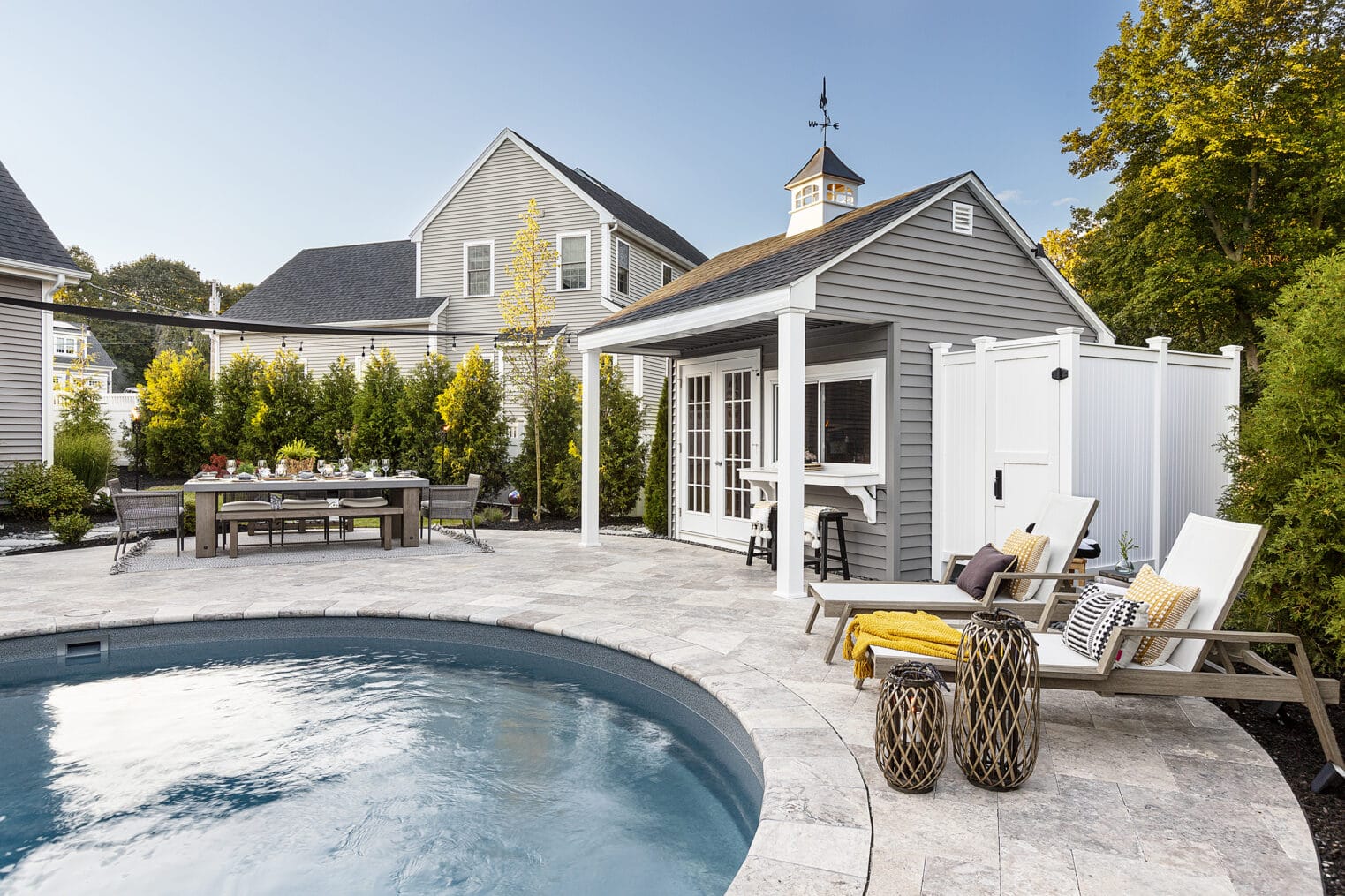 Pool chairs by the inground pool with travertine paver pool deck. Landscape design-build by Dex by Terra in Shrewsbury, MA.