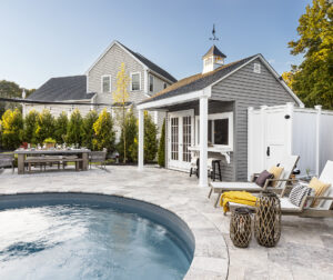 Pool chairs by the inground pool with travertine paver pool deck. Landscape design-build by Dex by Terra in Shrewsbury, MA.