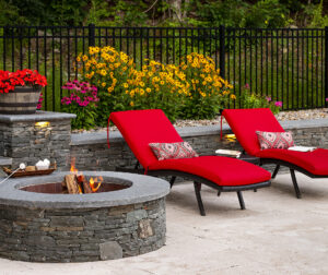 Pool chairs by the stone fire pit and seating wall with s'mores. Dex by Terra Hardscaping project in Sterling Massachusetts.
