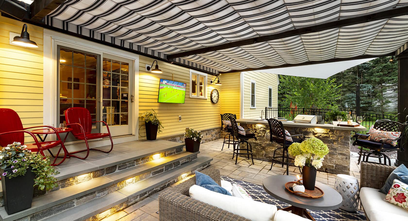 Pergola-covered paver patio, LED lighting, and outdoor kitchen. Landscape design-build by Dex by Terra in Stow, MA