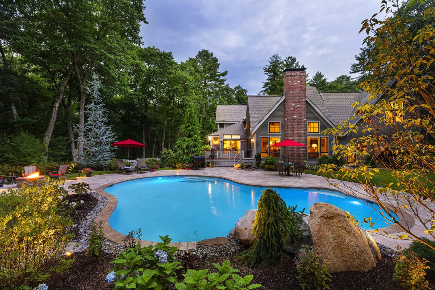 Gunite pool with stone paver deck. Landscaped flowerbeds in the foreground. Dex by Terra pool renovation in Carlisle, MA.