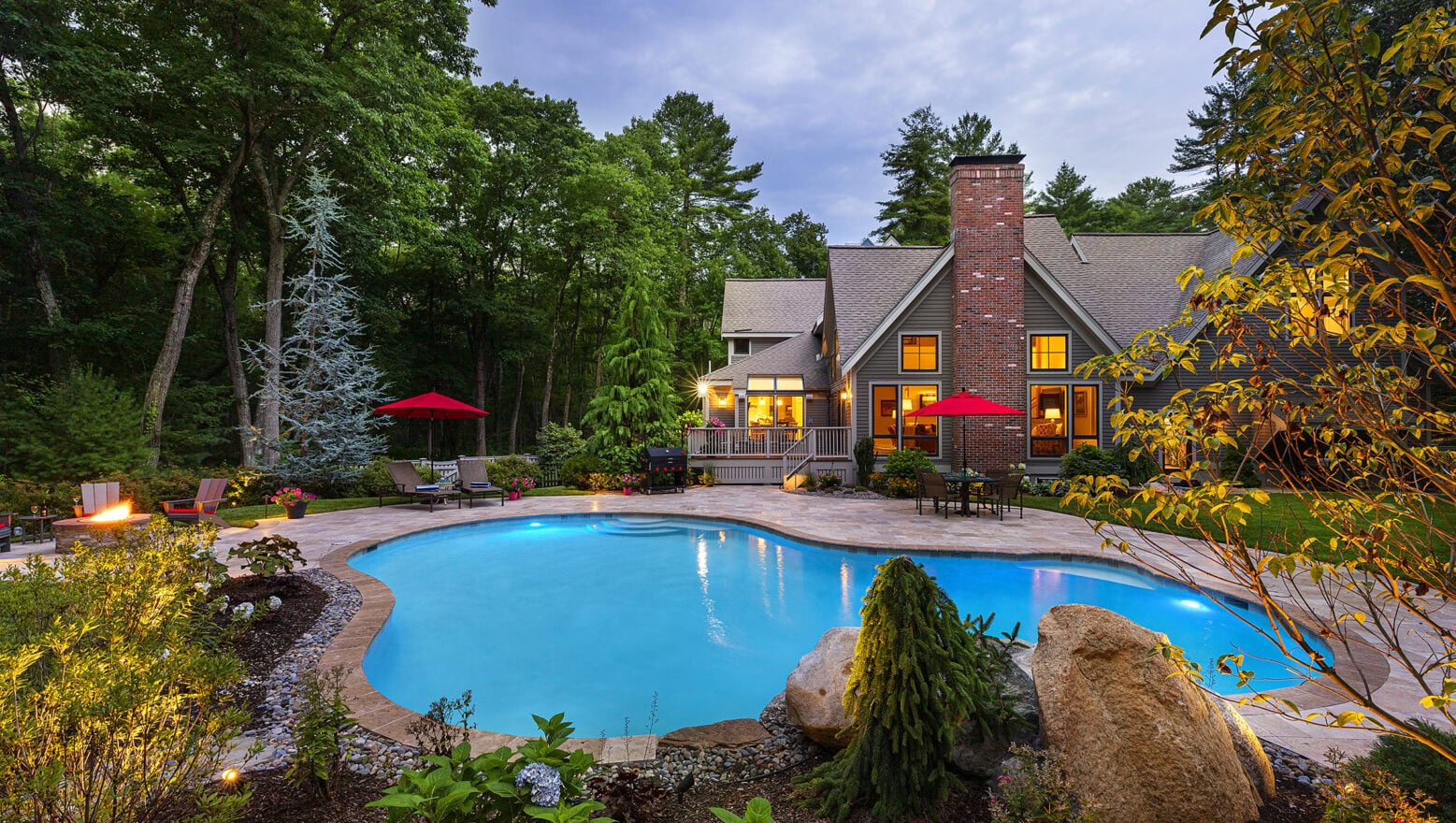 Gunite pool with stone paver deck. Landscaped flowerbeds in the foreground. Dex by Terra pool renovation in Carlisle, MA.