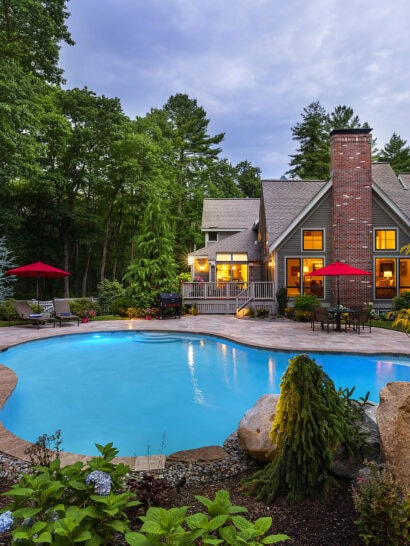 Gunite pool with stone paver deck. Landscaped flowerbeds in the foreground. Dex by Terra pool renovation in Carlisle, MA.