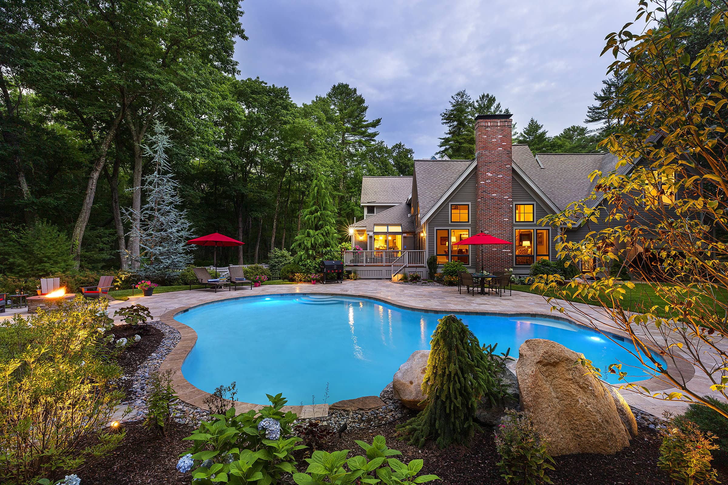 Gunite pool with stone paver deck. Landscaped flowerbeds in the foreground. Dex by Terra pool renovation in Carlisle, MA.