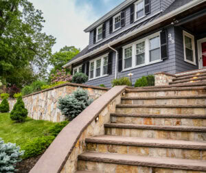 Stone steps, and a stone retaining wall with built-in low voltage landscape lighting in Needham, MA.