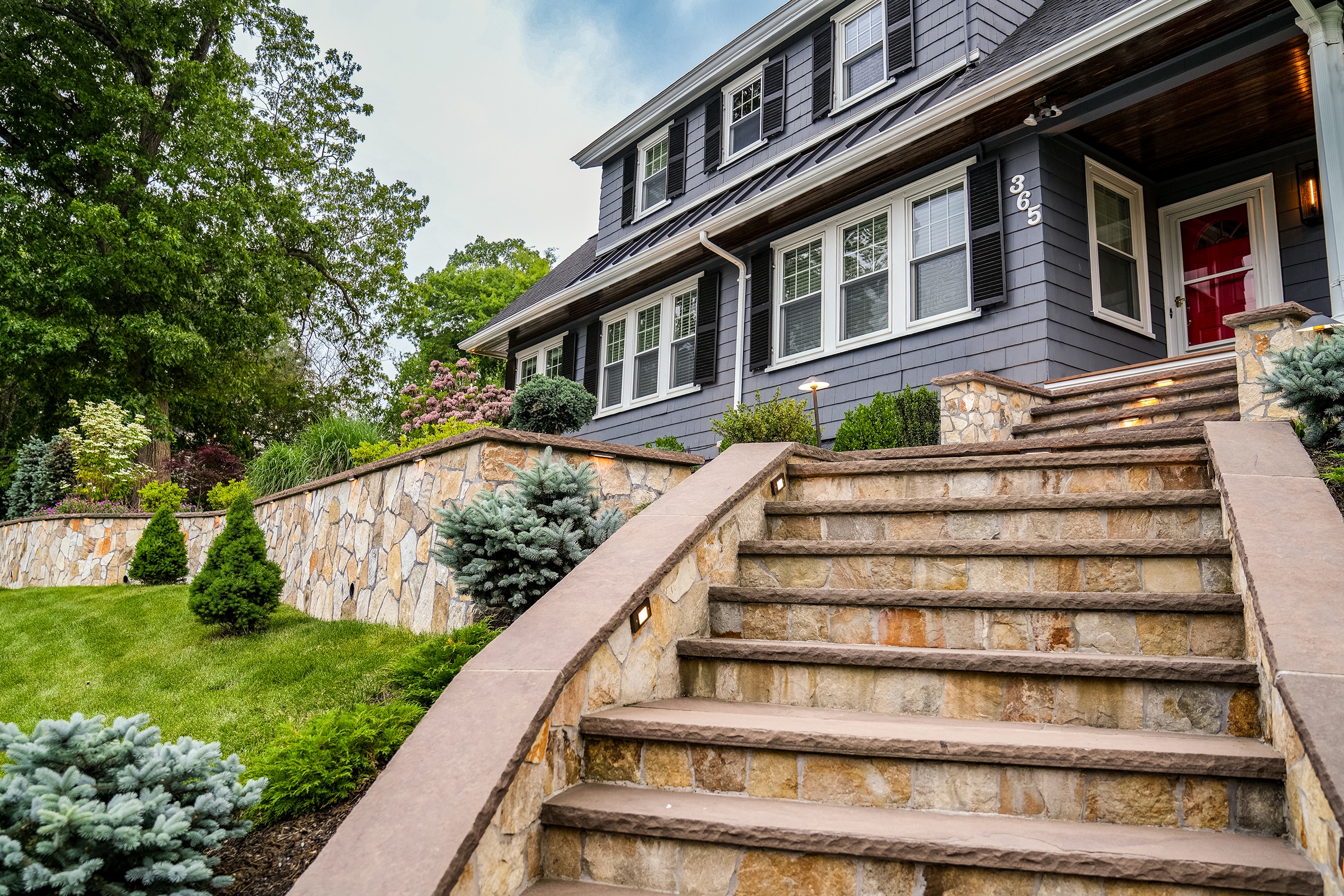 Stone steps, and a stone retaining wall with built-in low voltage landscape lighting in Needham, MA.