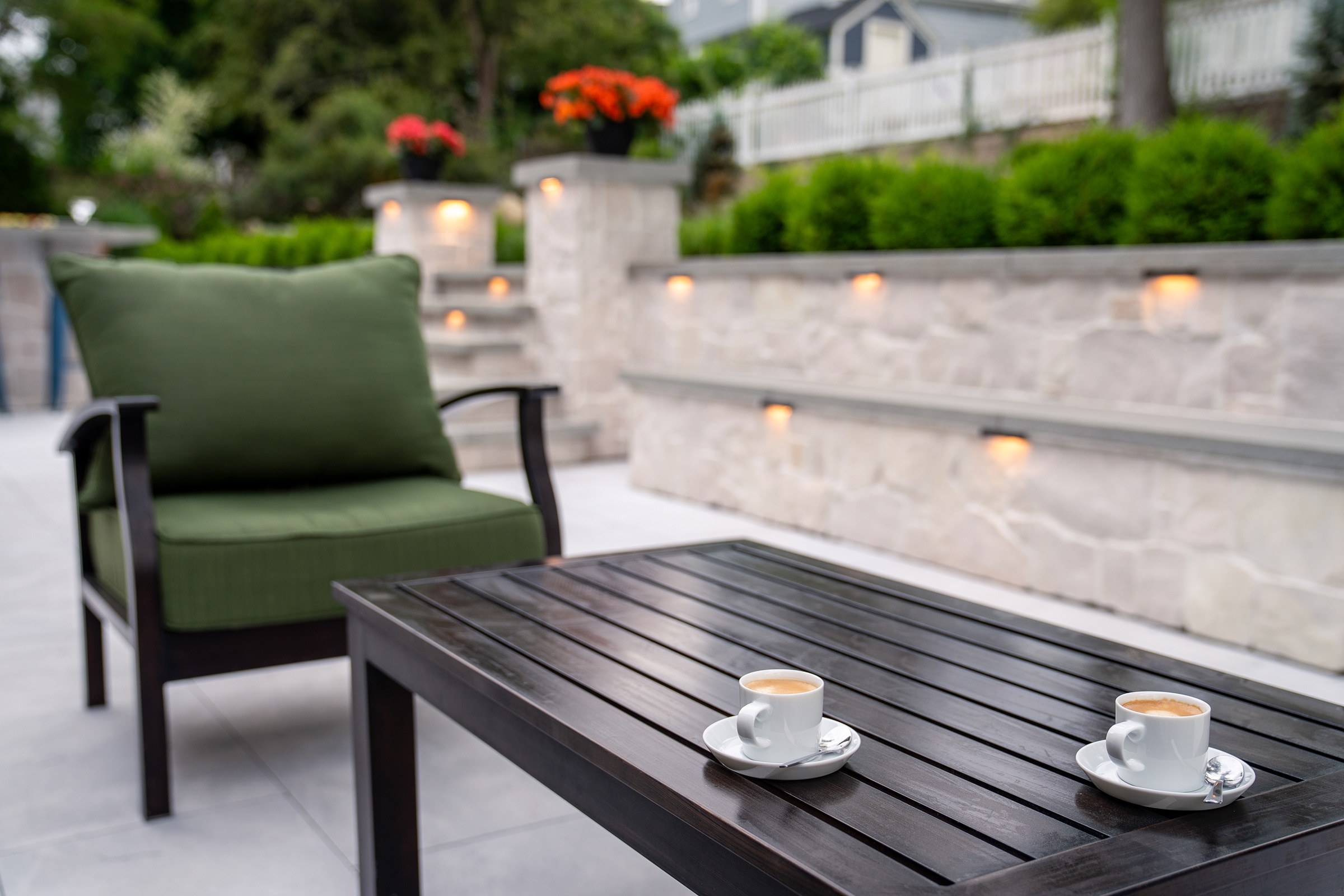 Lattes on a coffee table with patio furniture with stone seating wall in the background in Needham, MA.