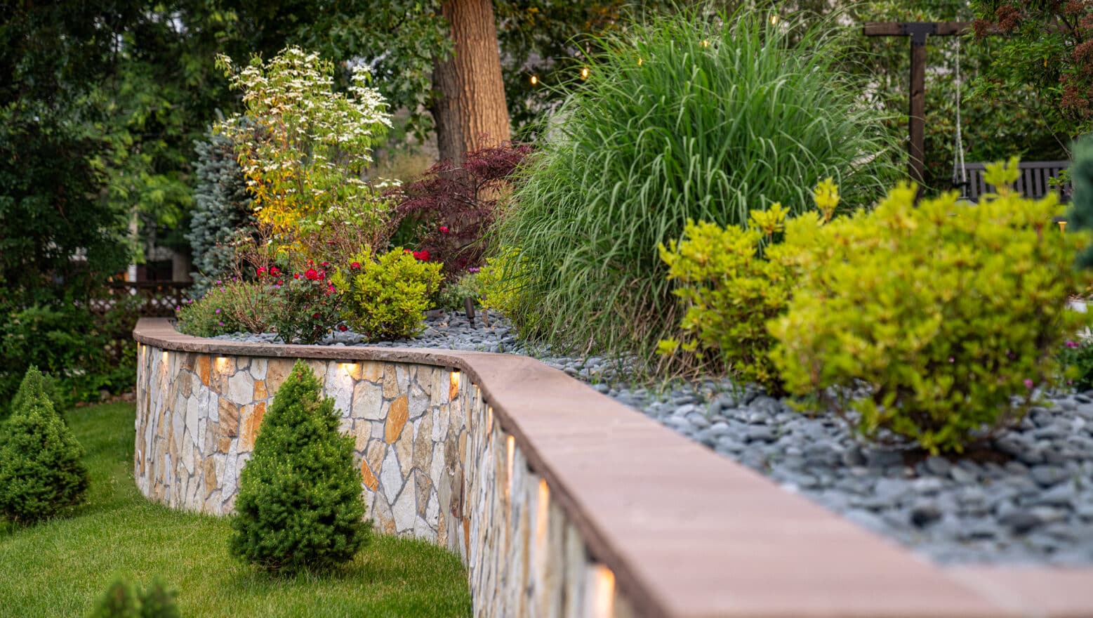 A stone retaining wall with built-in low voltage landscape lighting in Needham, MA.