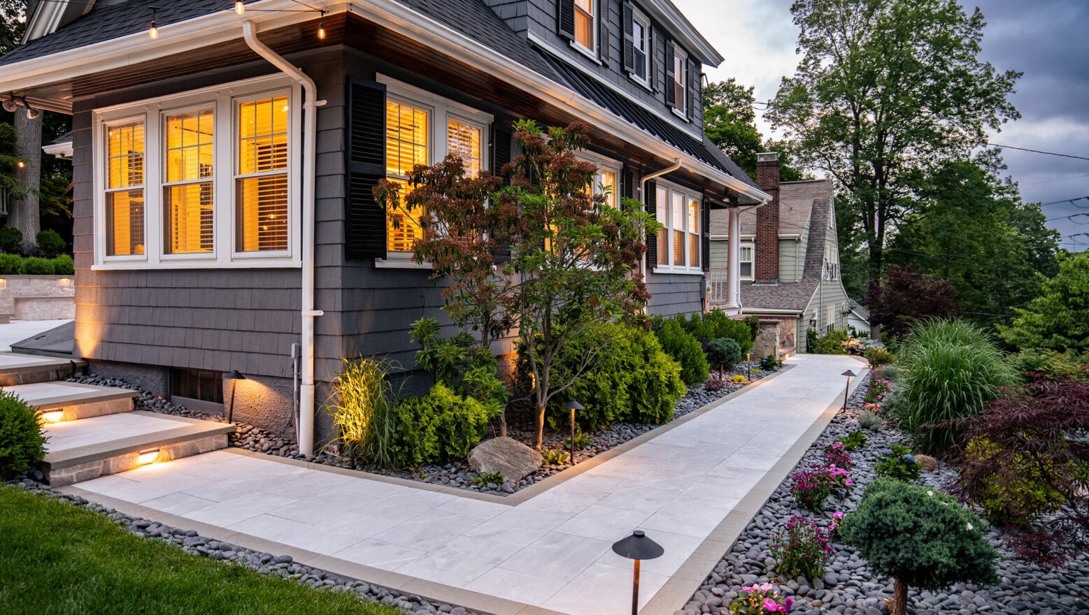 A Needham, MA, home with stone paver front walkway, landscaping, and landscape lighting designed and built by Dex by Terra,