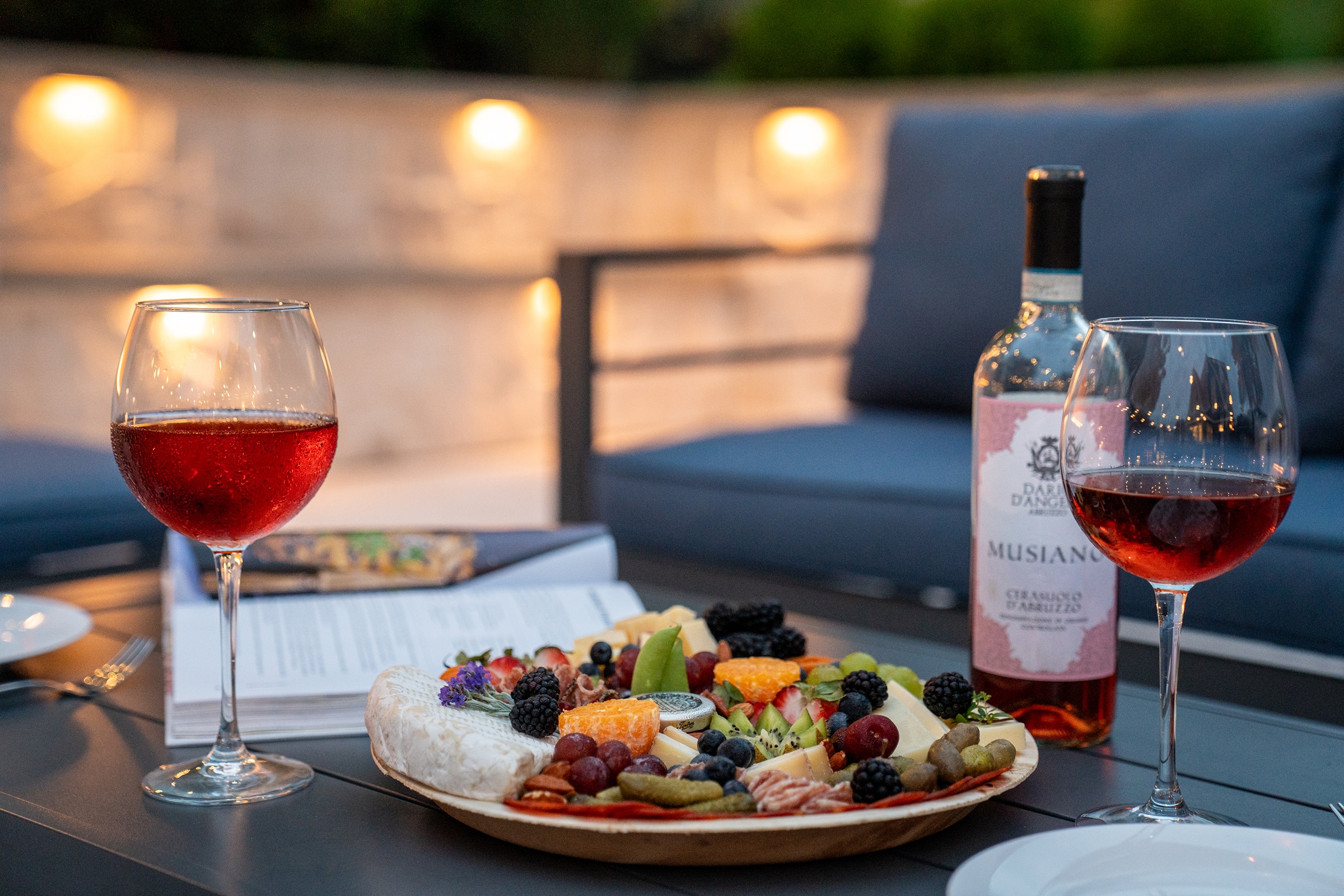 A charcuterie board and glasses of wine wait to be enjoyed by the patio fireplace.