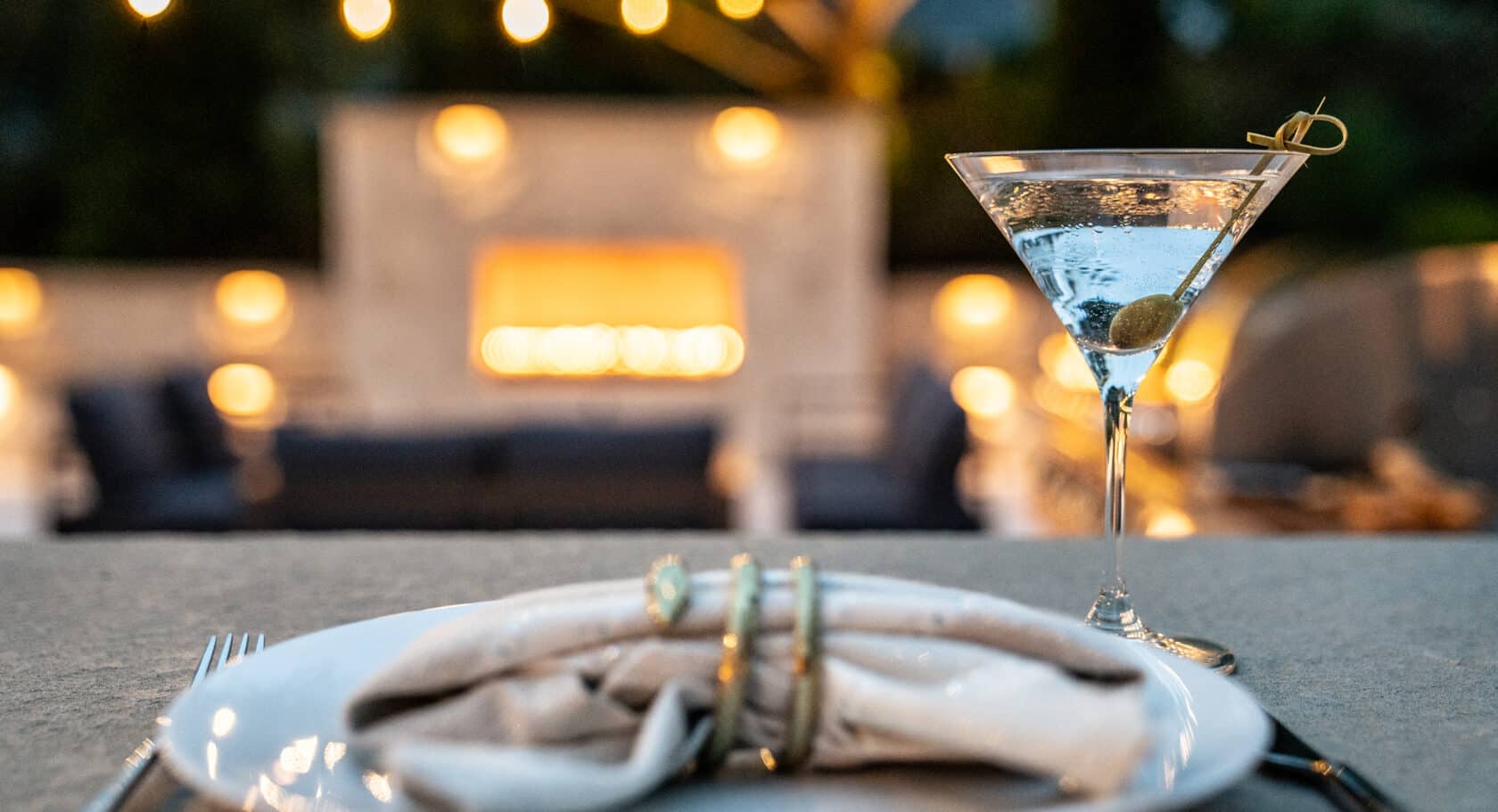 Evening martinis at the patio bar overlooking a glowing gas fireplace with outdoor string lights.