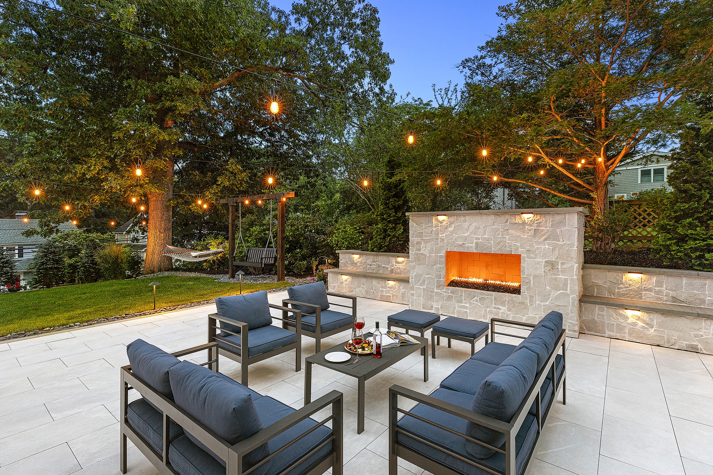 Patio furniture, with wine and cheese by a gas outdoor fireplace. Dex by Terra Hardscaping & Landscaping in Needham, MA.