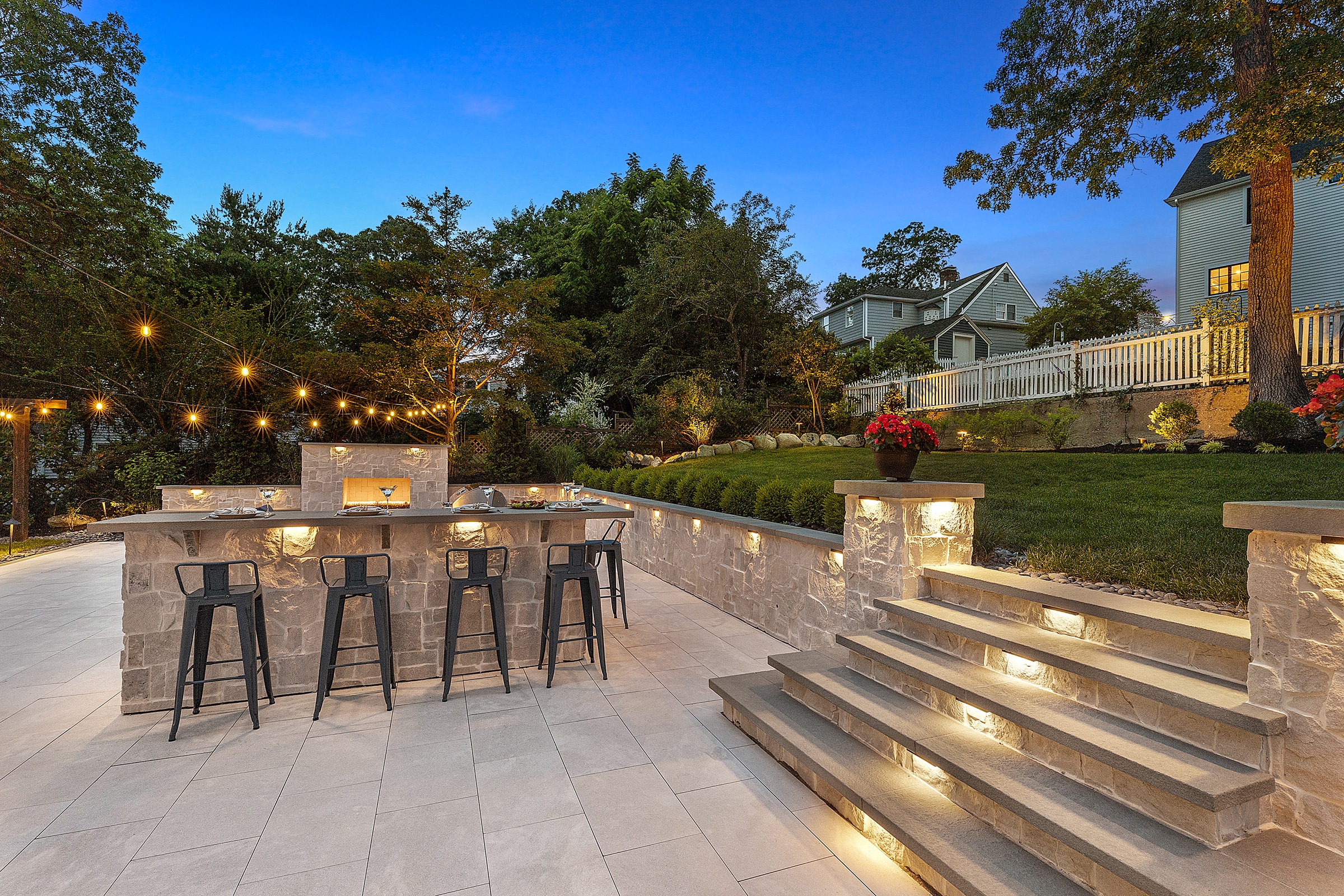 Outdoor Kitchen, stone stairs, and outdoor fireplace at dusk.