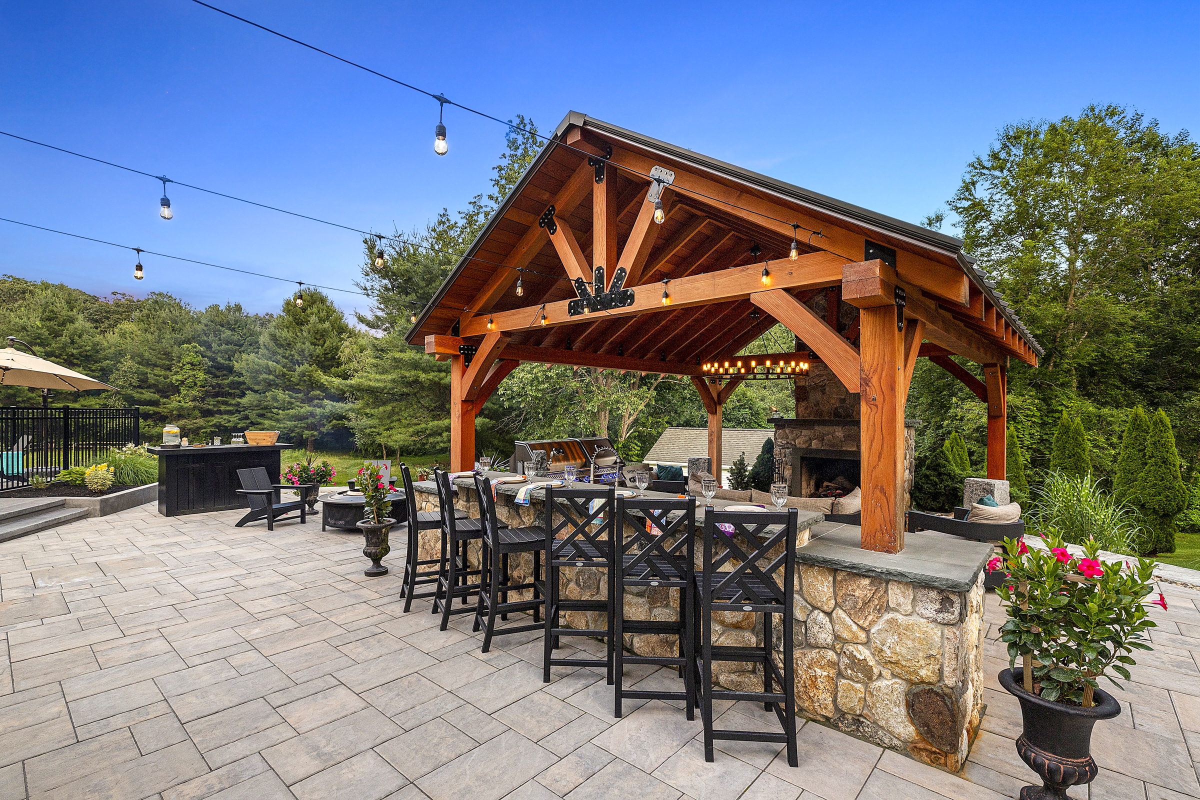 The client built pergola rests on an expansive patio built from Unilock Beacon Hill Flagstone Pavers with Almond Grove coloration. The outdoor dining bar was adorned with New England Rounds stone veneer.