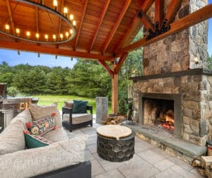 A client built pergola covers the paver patio, wood burning outdoor fireplace, and outdoor kitchen at this home in Auburn, Massachusetts.
