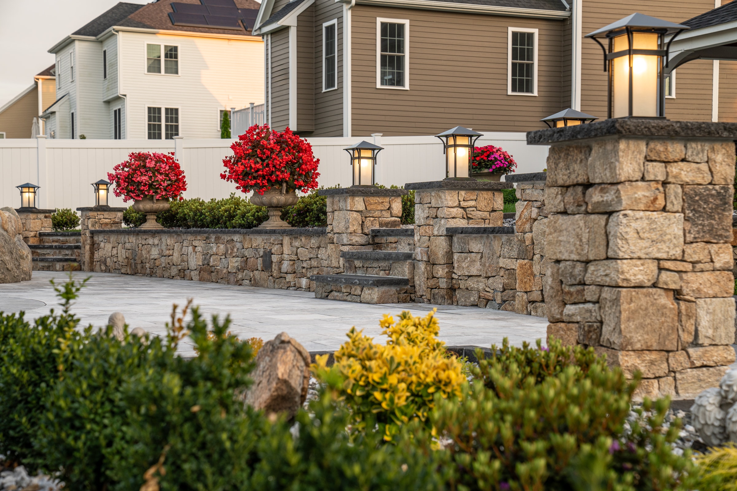 Walls, columns, and steps were built with stone veneer and stone caps. Landscaping and hardscaping project by Dex by Terra.