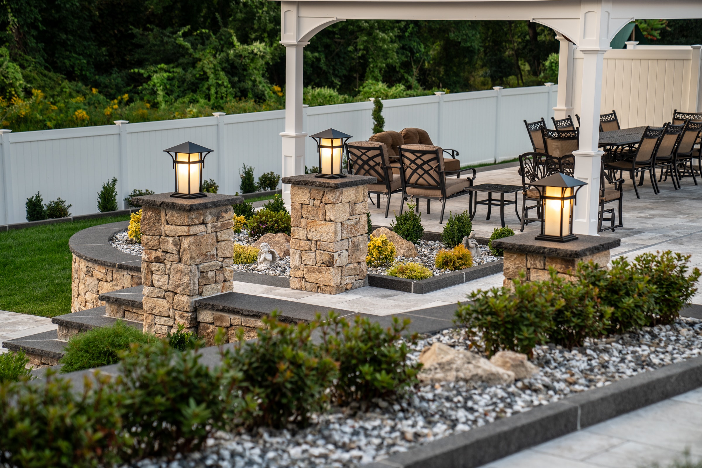 Stone columns and landscaping elevate this high-end backyard built by Dex by Terra in Grafton, Massachusetts.