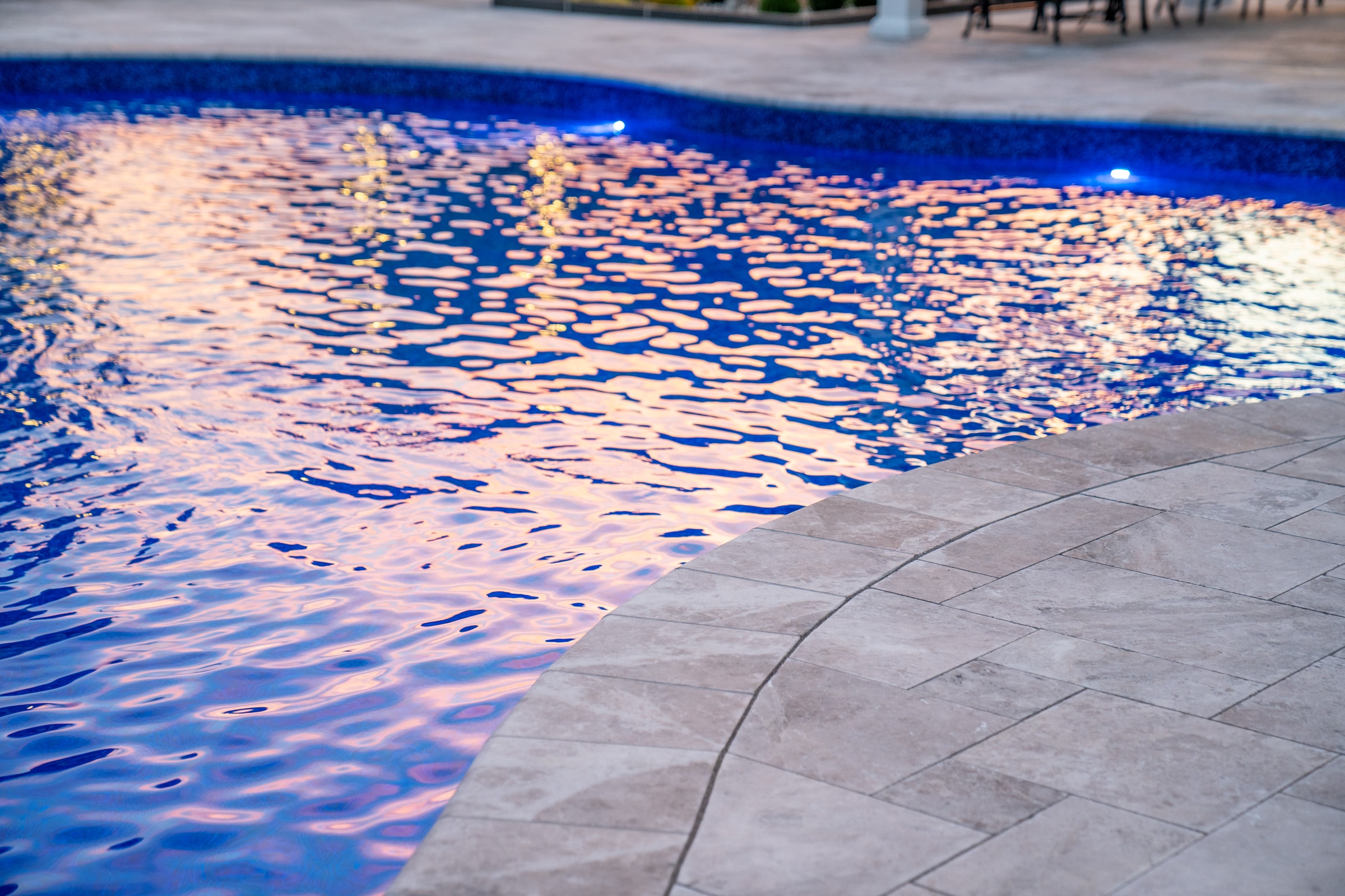 This natural stone pool deck was crafted from silver travertine by Dex by Terra in this Grafton, Massachusetts backyard.