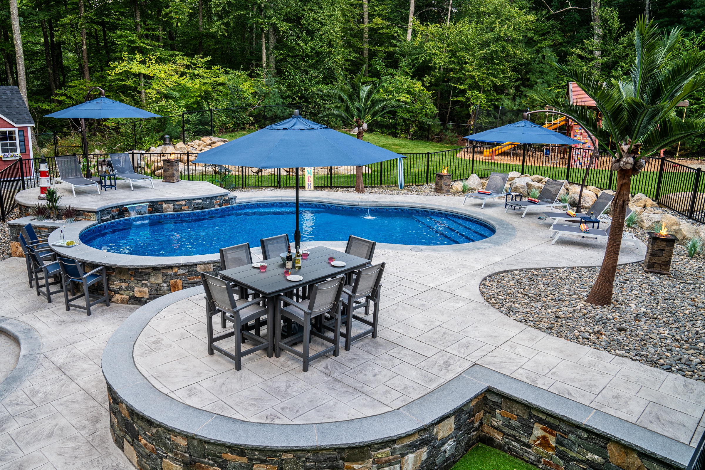 Northbridge, MA hardscape with stamped concrete walkways, pool deck, poolside bar, and sundeck, all built by Dex by Terra.