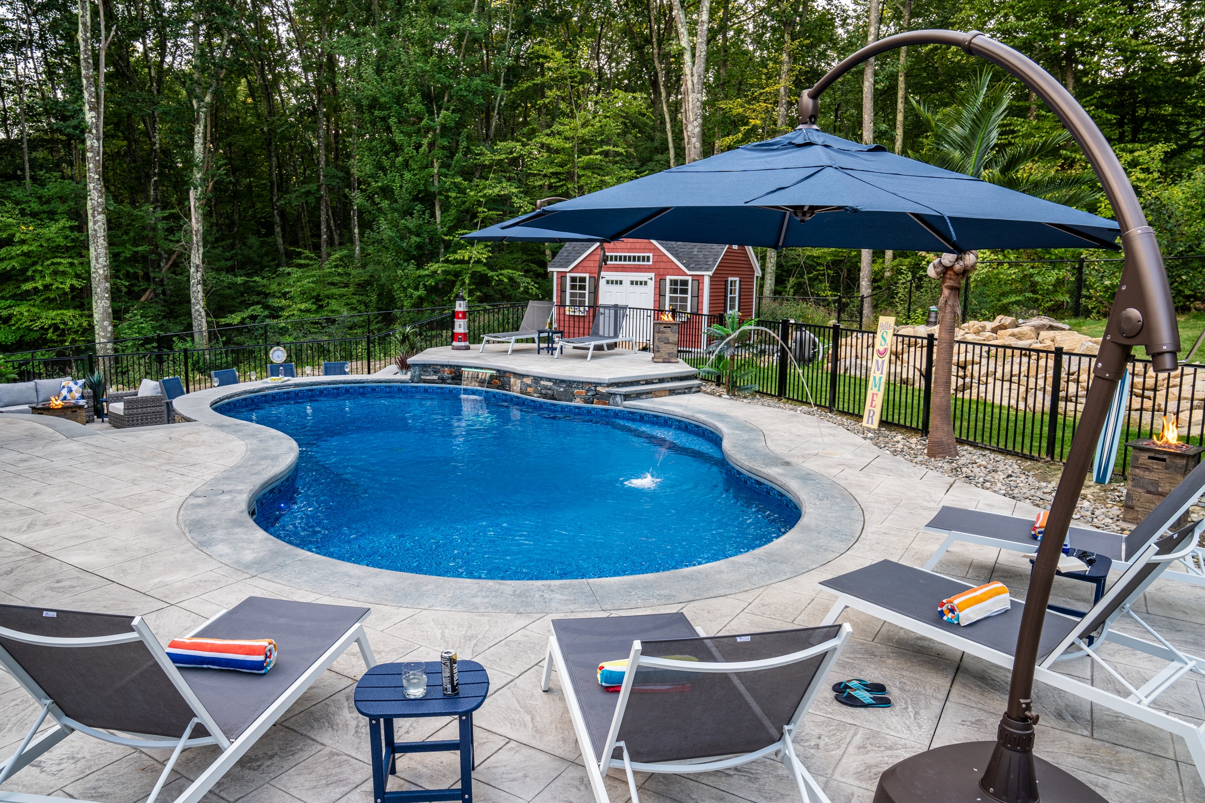 Lounge chairs sit on the stamped concrete pool deck at this Dex by Terra hardscape project in Northbridge, Massachusetts.