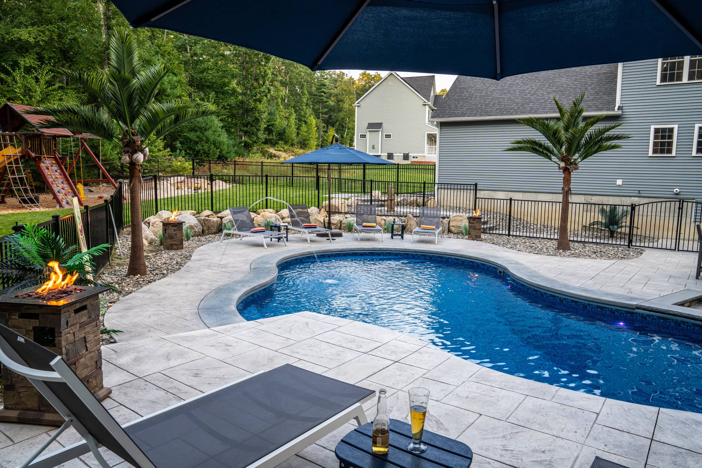 A view from the sundeck looking toward poolside lounge chairs at this Dex by Terra pool deck project in Northbridge, MA.