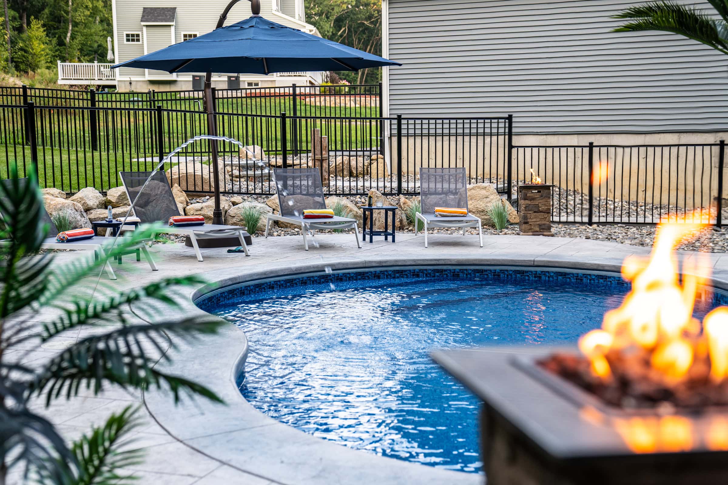 A view from the sundeck looking toward poolside lounge chairs at this Dex by Terra pool deck project in Northbridge, MA.