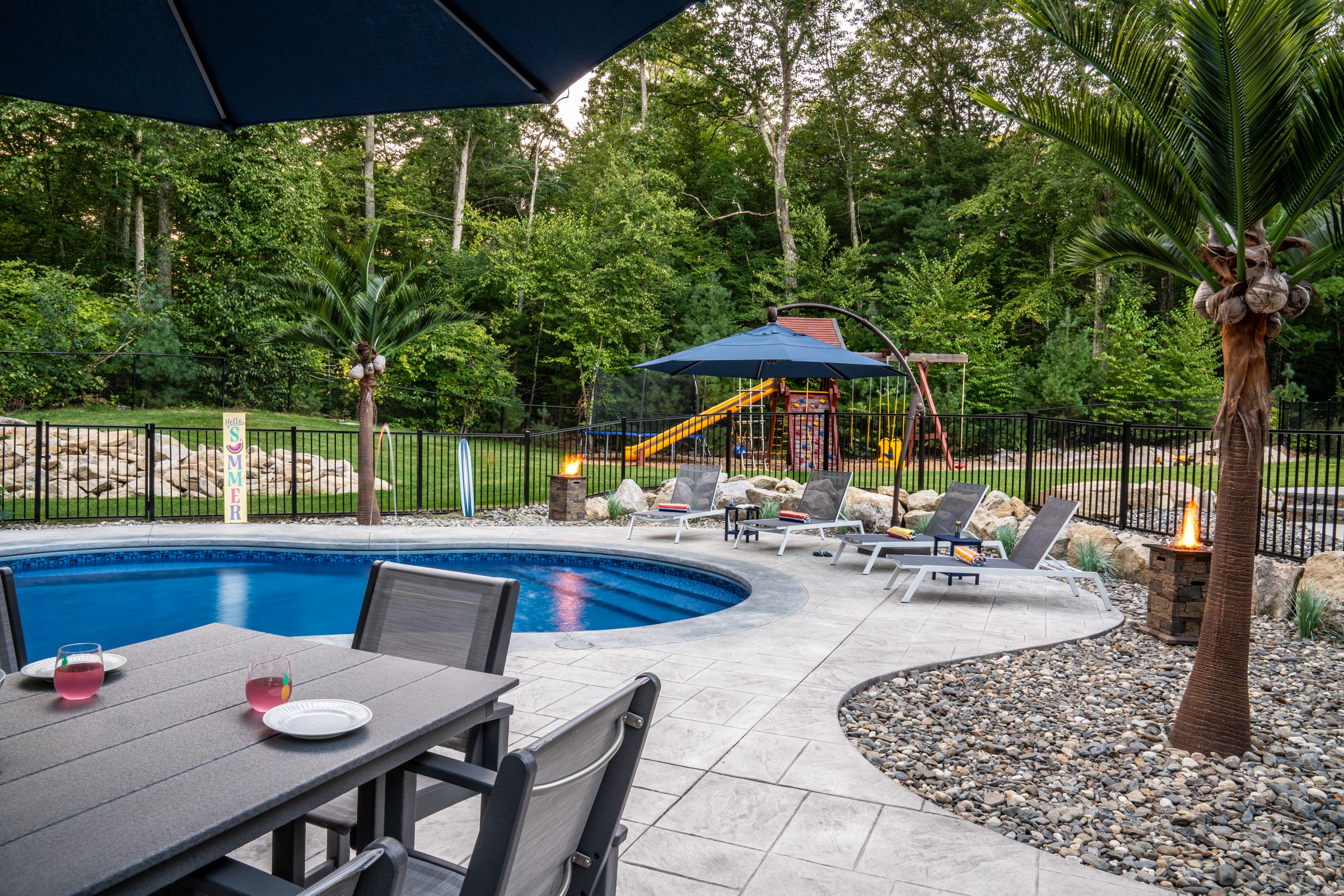 The poolside dining patio is perched atop the elevated stamped concrete pool deck at this home in Northbridge, Massachusetts.