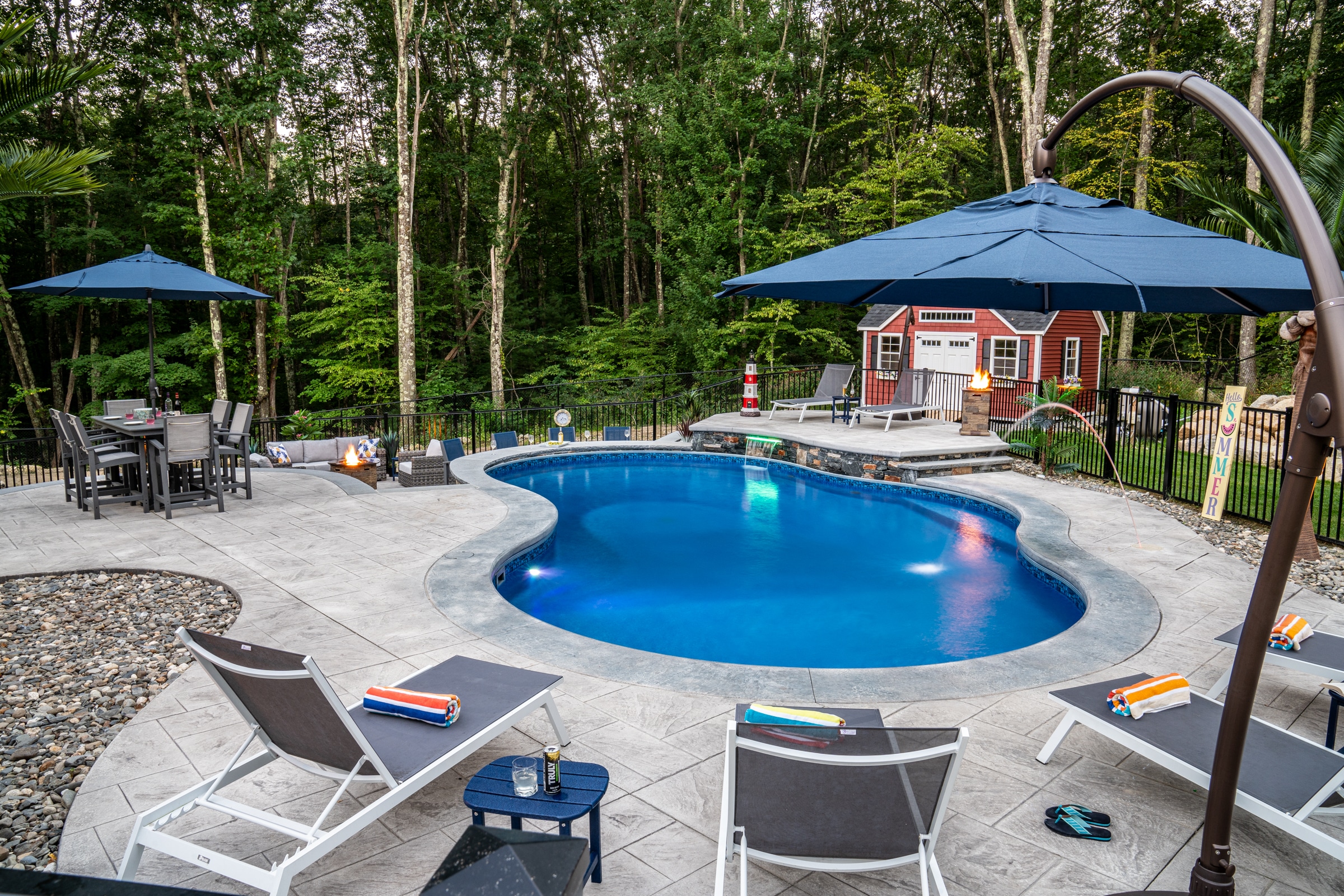 This hardscape with a stamped concrete pool deck, poolside bar, sundeck, and water feature built by Dex by Terra, is a paradise.
