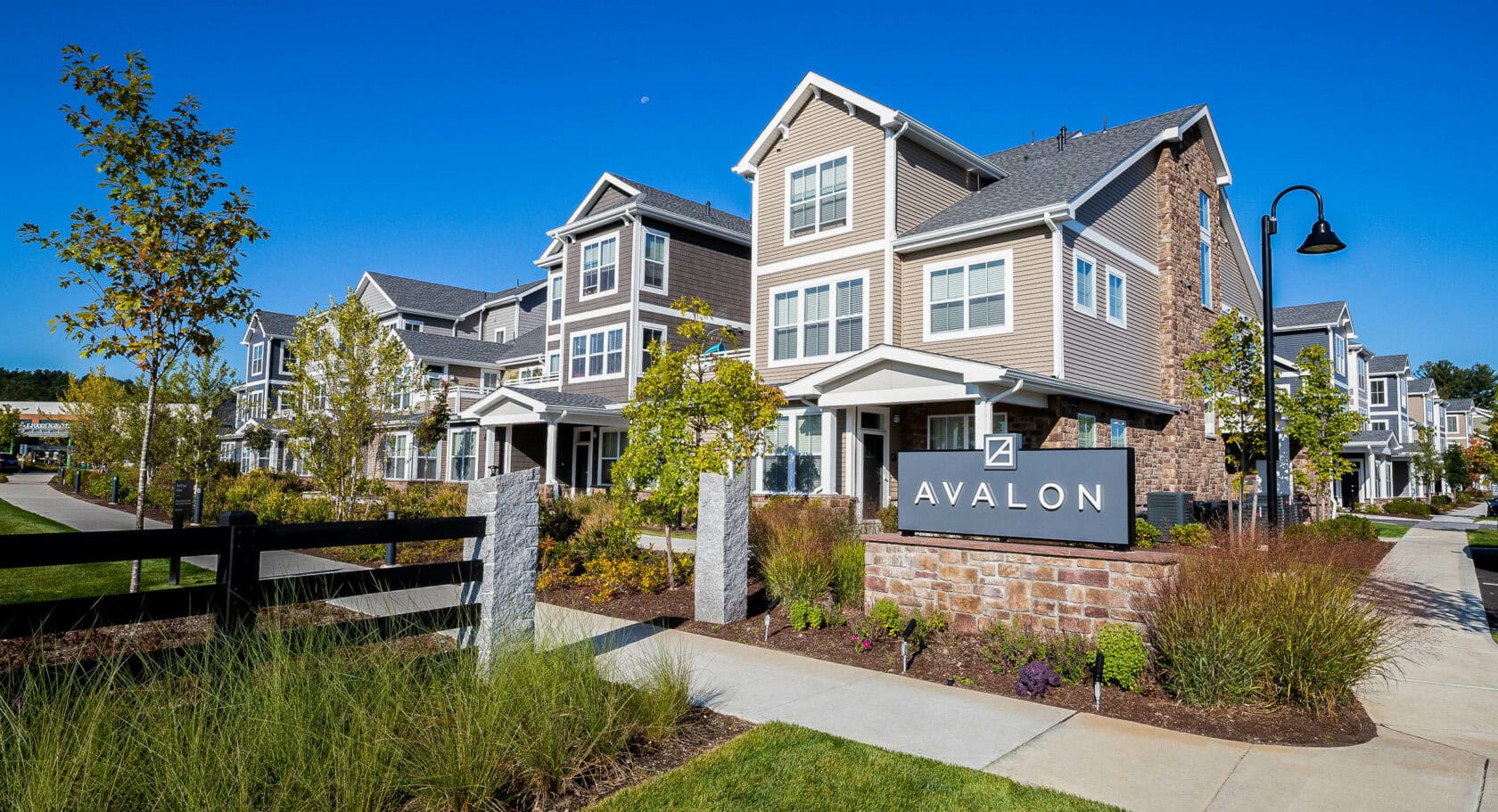 Stone veneer Avalon sign with landscaped flower beds. Commercial hardscape and landscape project by Dex by Terra.