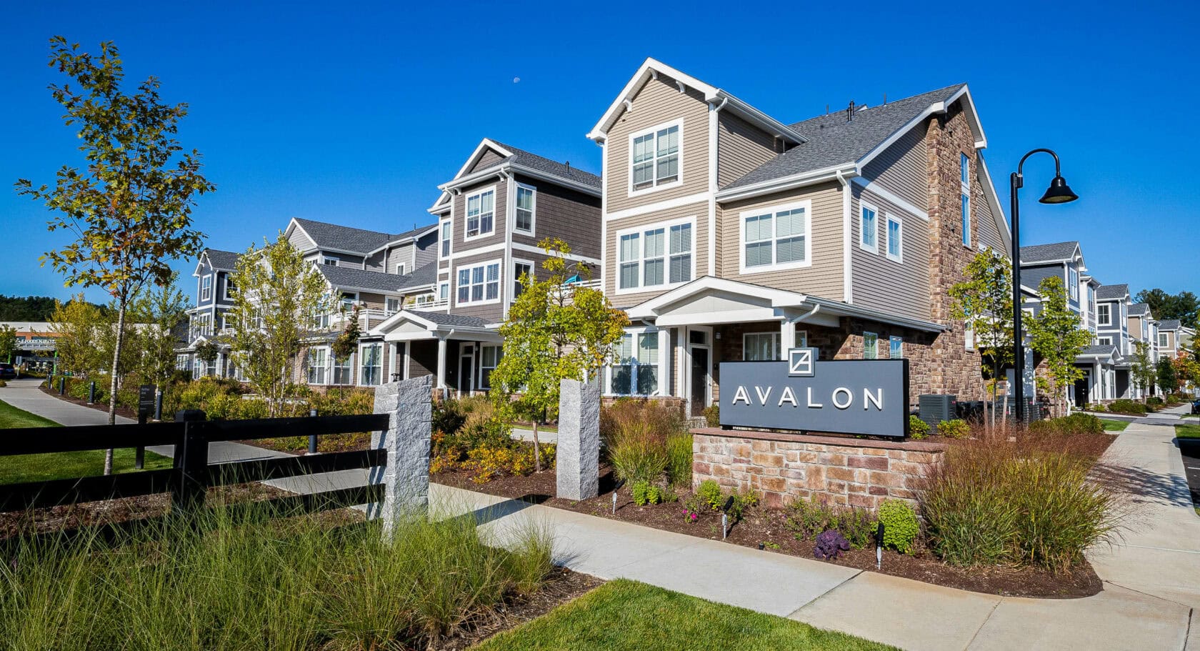 Stone veneer Avalon sign with landscaped flower beds. Commercial hardscape and landscape project by Dex by Terra.